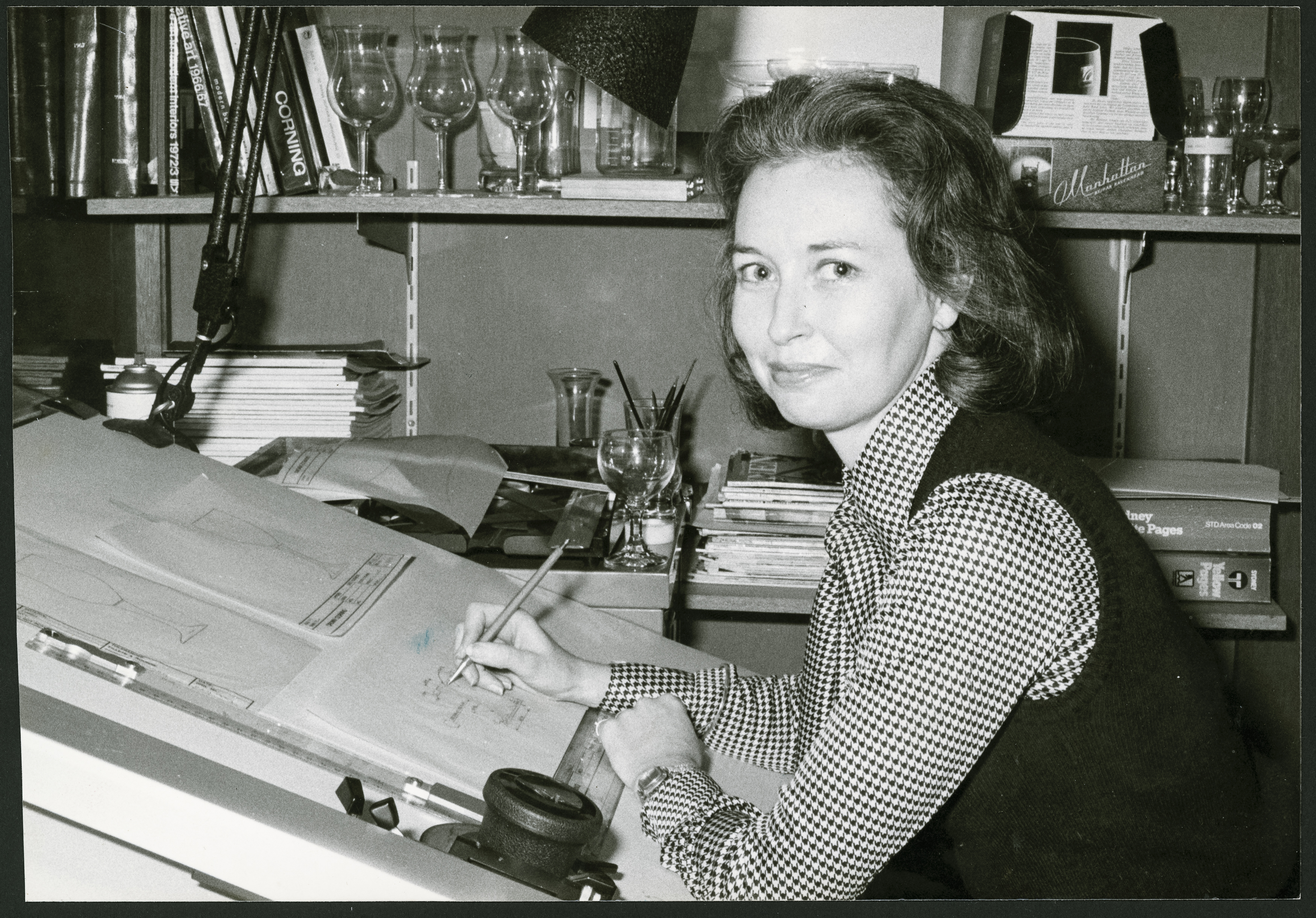 Black and white photograph of a woman working at a drawing board.